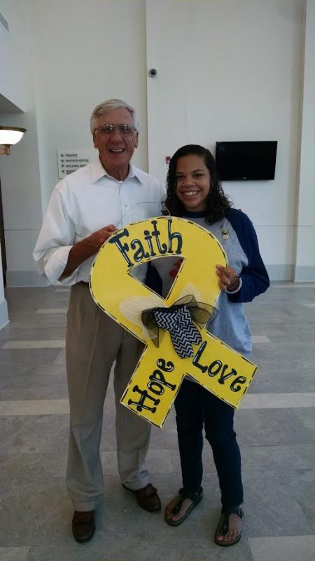 McKenzie Cain sold Mayor Ronnie Marks a door hanger that is the gold awareness ribbon for childhood cancer. The ribbon is on Athens City Hall